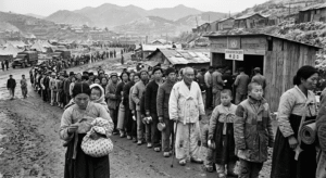 1950년대 한국전쟁 당시 임시 배급소 앞에 길게 줄을 서서 식량 배급표를 들고 기다리는 피난민들